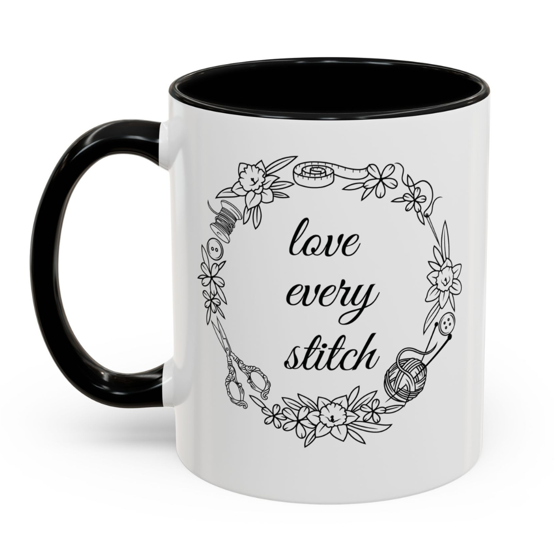 White mug with black interior and handle, featuring a floral design and 'love every stitch' text.