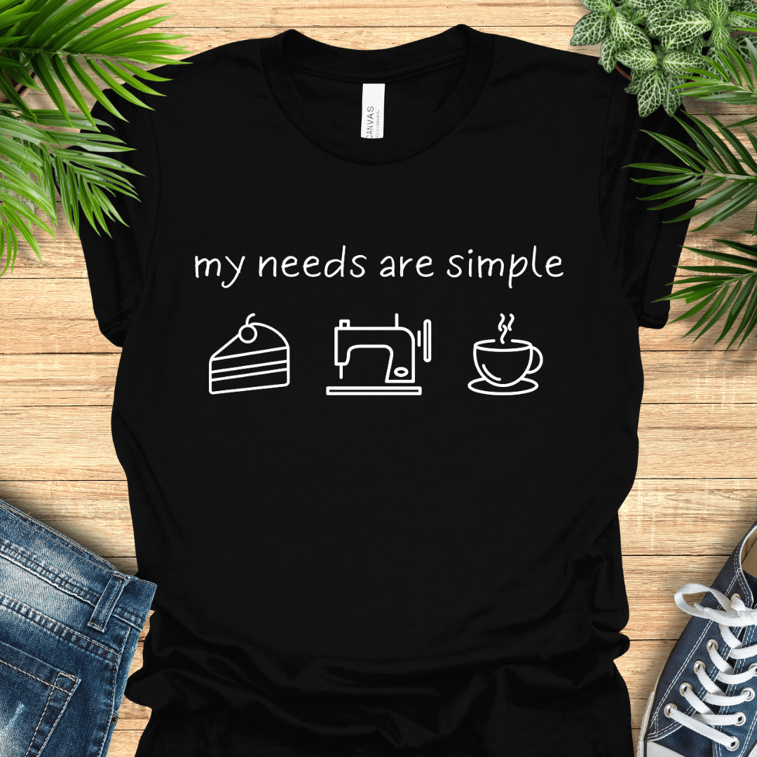Funny sewing t-shirt with the phrase ‘my needs are simple’ and icons of cake, a sewing machine, and a cup of tea/coffee.