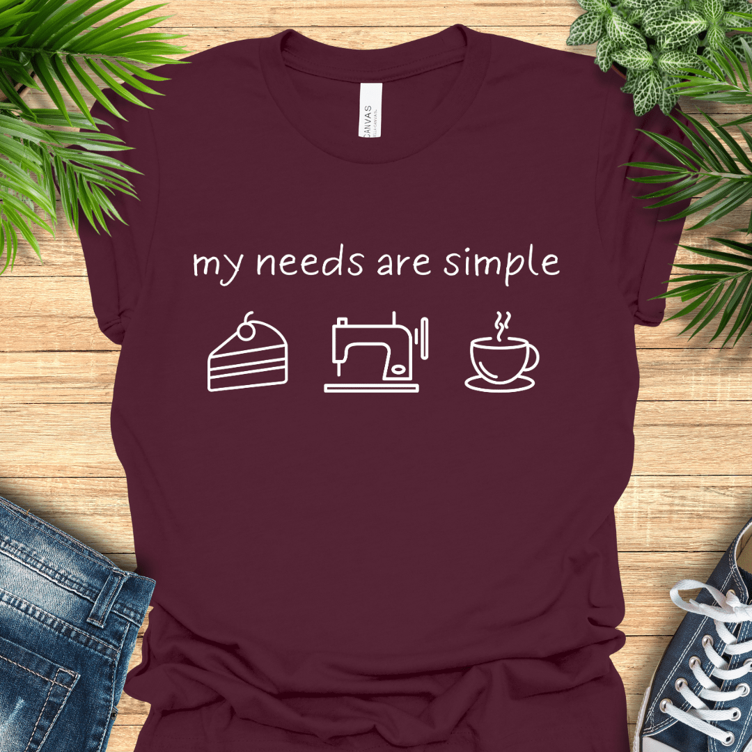 Funny sewing t-shirt with the phrase ‘my needs are simple’ and icons of cake, a sewing machine, and a cup of tea/coffee.