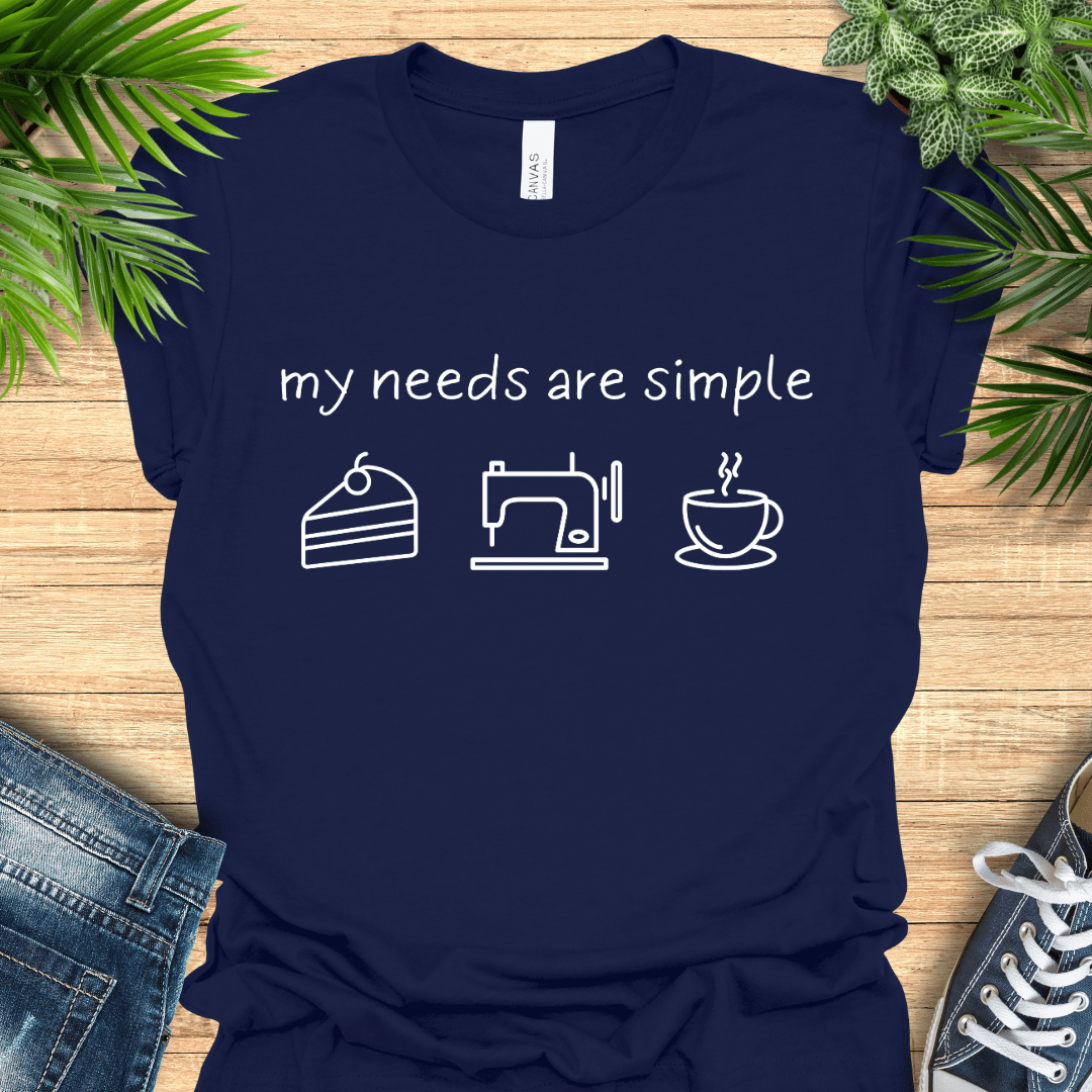 Funny sewing t-shirt with the phrase ‘my needs are simple’ and icons of cake, a sewing machine, and a cup of tea/coffee.