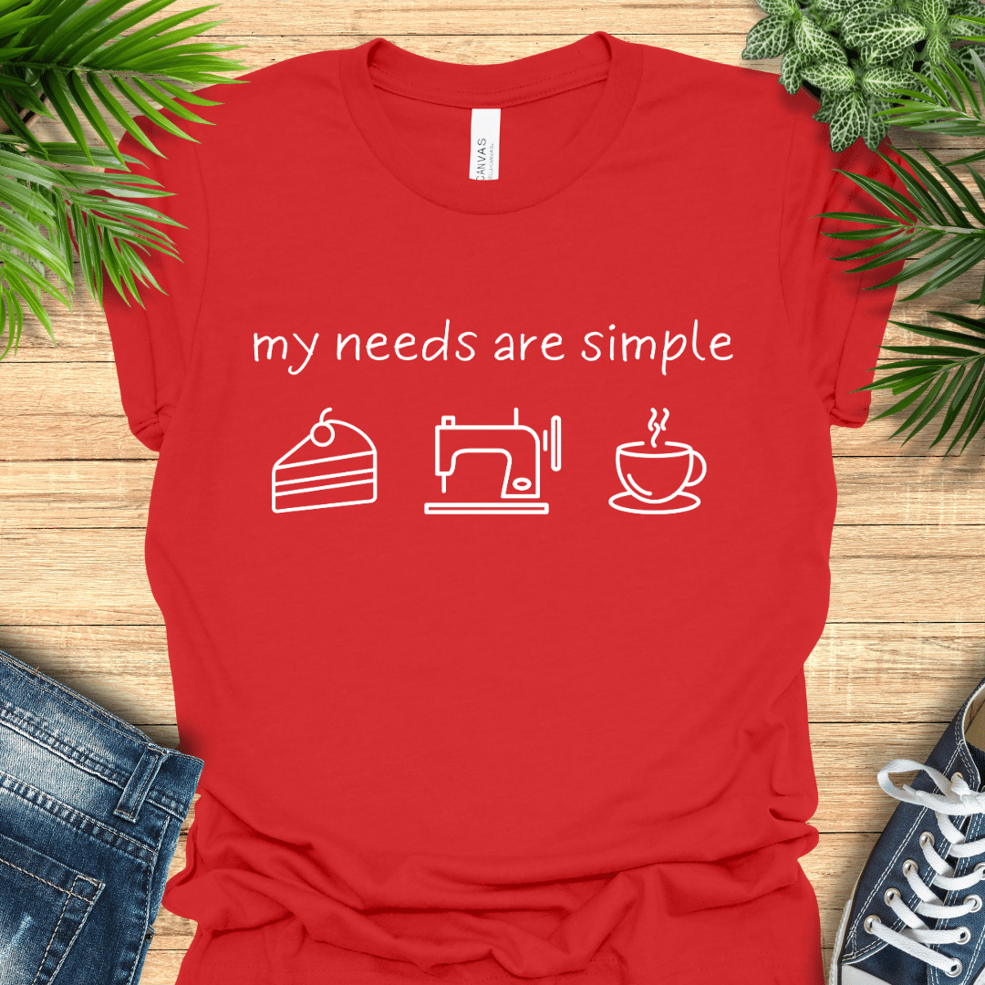 Funny sewing t-shirt with the phrase ‘my needs are simple’ and icons of cake, a sewing machine, and a cup of tea/coffee.