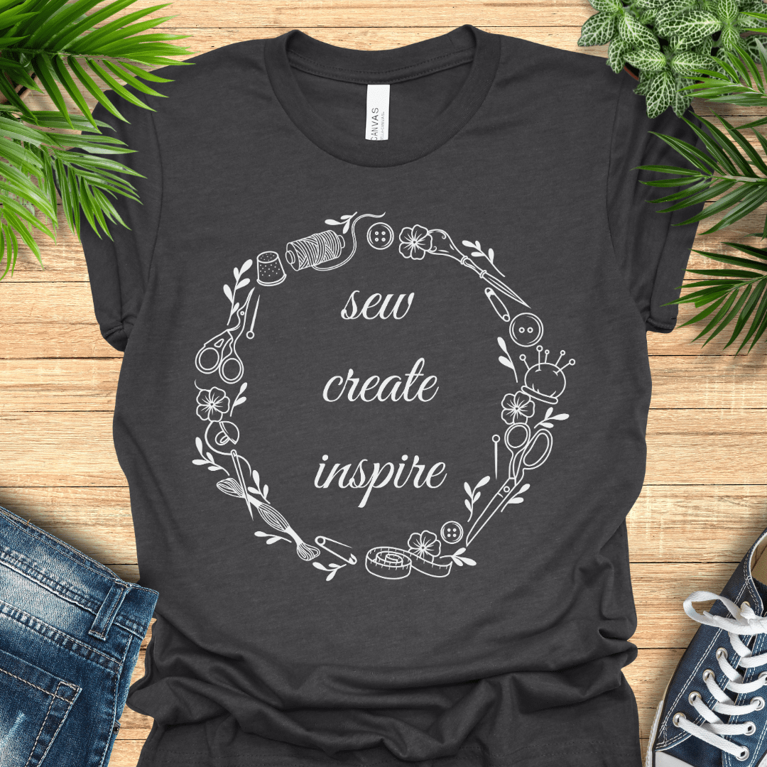 Sewing t-shirt with ‘sew, create, inspire’ surrounded by a circular border of sewing tools and notions.